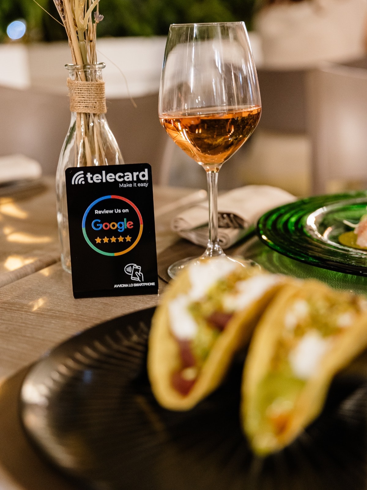 Telecard NFC review card next to a glass of wine on a restaurant table